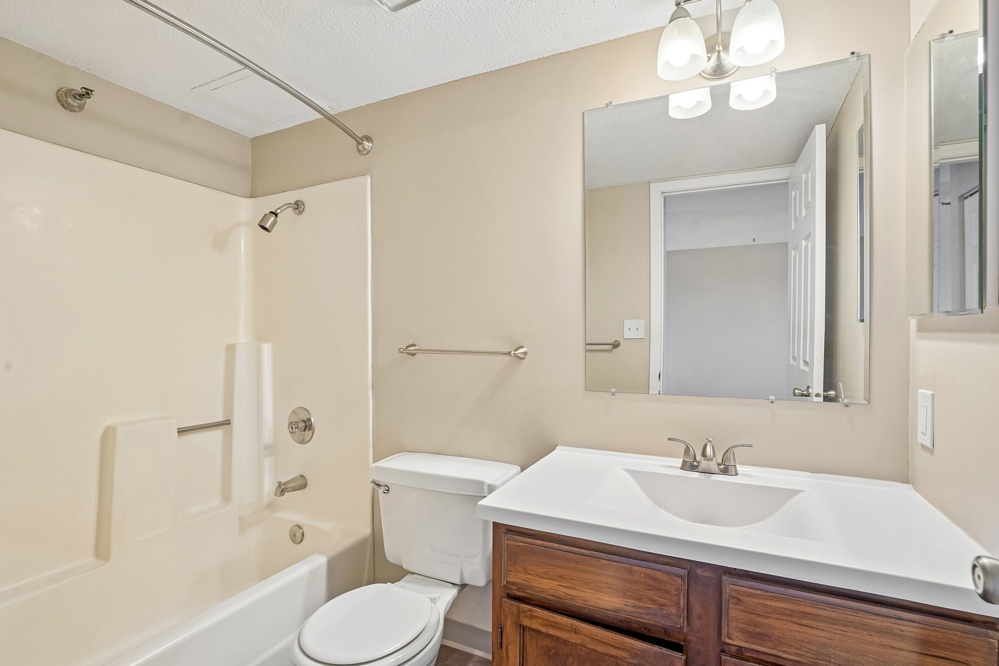 Irvine Park Towers apartment bathroom with wood vanity, large mirror and tub-shower combination